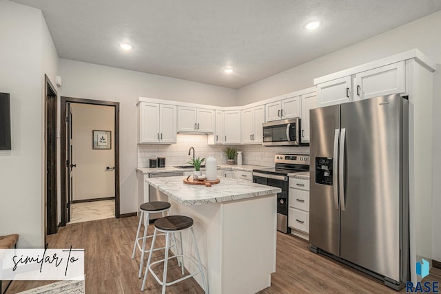 kitchen with white cabinetry, sink, a kitchen island, and appliances with stainless steel finishes