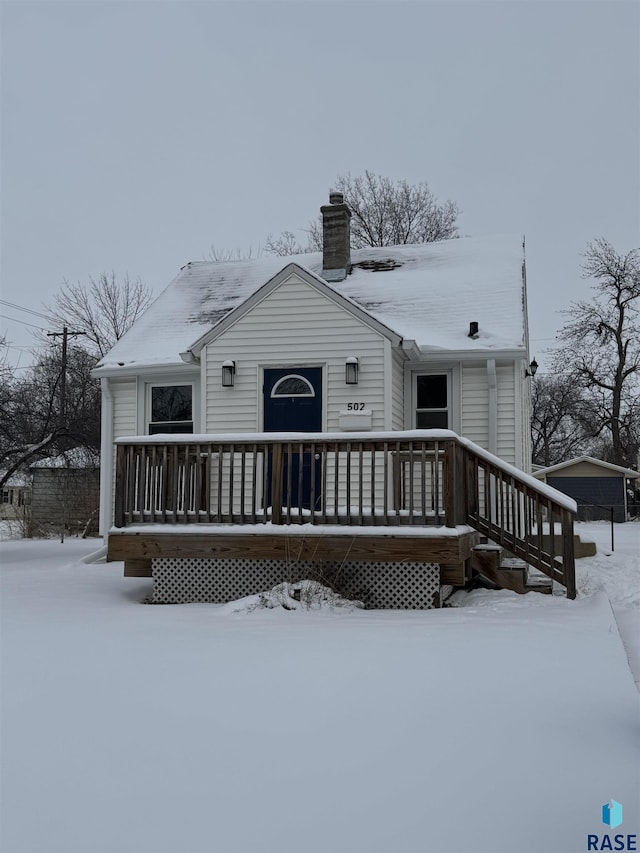 snow covered rear of property with a wooden deck