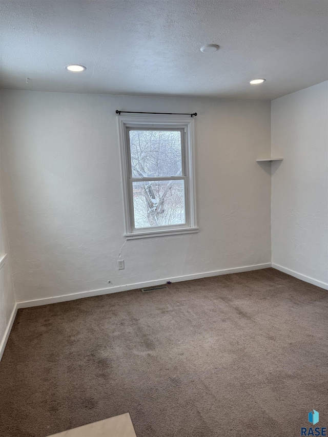 carpeted spare room with a textured ceiling