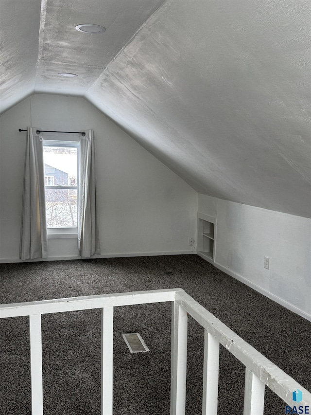 bonus room featuring lofted ceiling, carpet flooring, built in features, and a textured ceiling