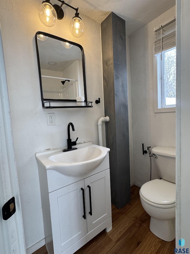 bathroom featuring walk in shower, vanity, toilet, and hardwood / wood-style floors