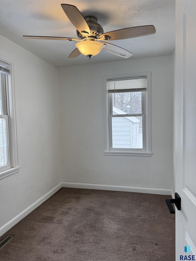 spare room with ceiling fan, dark carpet, and a textured ceiling