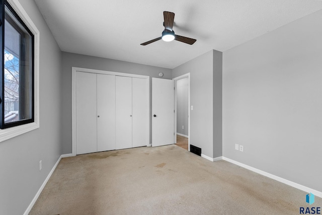 unfurnished bedroom featuring light colored carpet, a closet, and ceiling fan