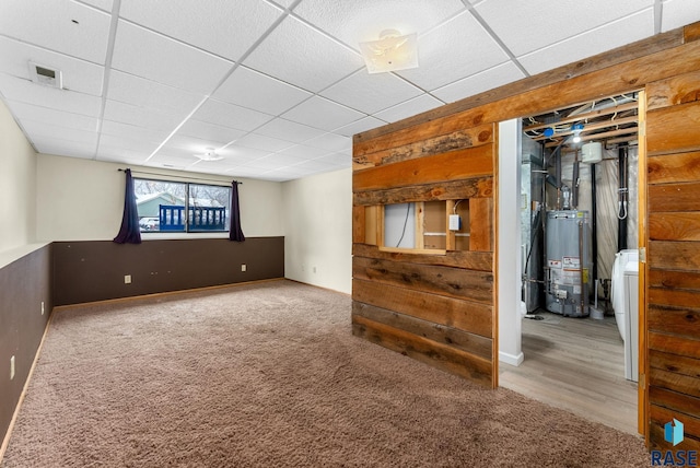 basement featuring water heater, carpet floors, and a drop ceiling