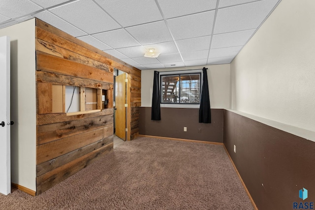 home theater room with a drop ceiling, carpet, and wood walls