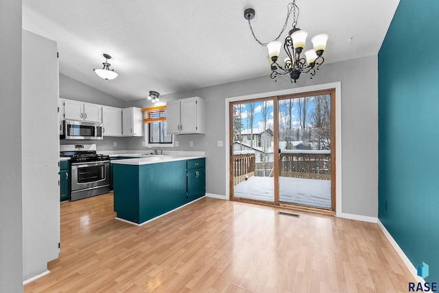 kitchen featuring white cabinetry, decorative light fixtures, light hardwood / wood-style flooring, and appliances with stainless steel finishes