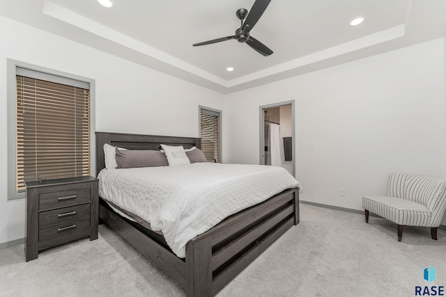 carpeted bedroom with a tray ceiling and ceiling fan