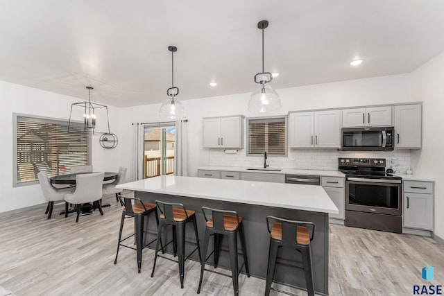 kitchen with sink, gray cabinetry, hanging light fixtures, stainless steel appliances, and a center island