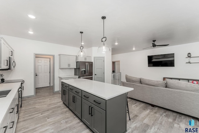 kitchen featuring appliances with stainless steel finishes, pendant lighting, gray cabinetry, white cabinets, and a center island