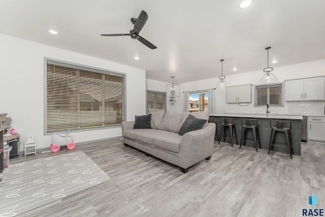 living room featuring sink, light hardwood / wood-style floors, and ceiling fan