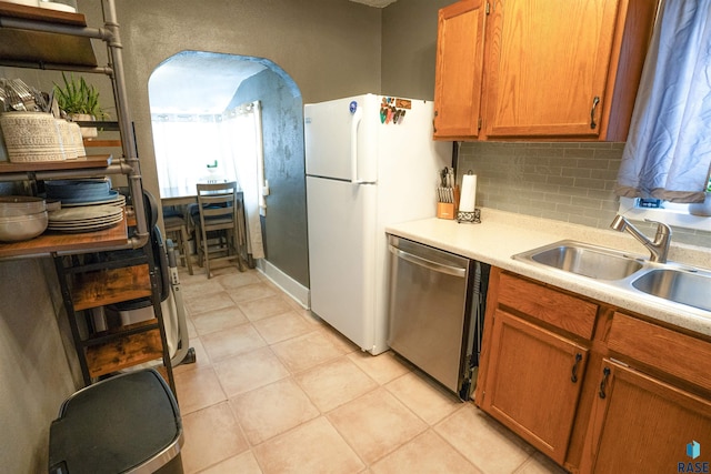 kitchen featuring light tile patterned flooring, sink, backsplash, white fridge, and stainless steel dishwasher