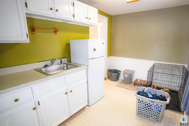 kitchen with white refrigerator, sink, and white cabinets