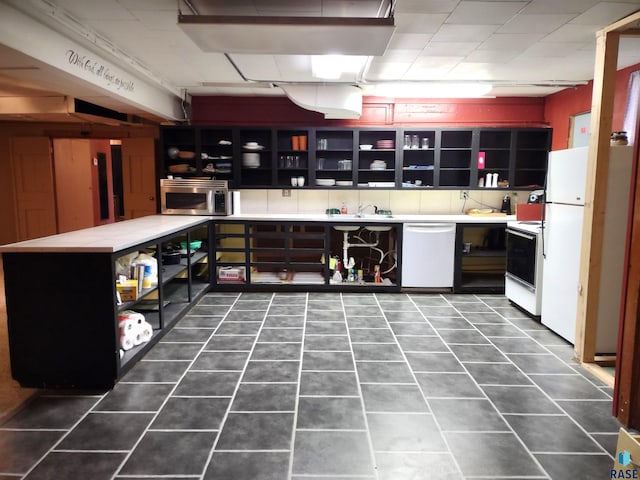 kitchen with white appliances, sink, and dark tile patterned floors