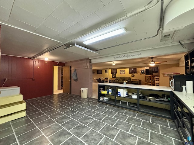 basement with ceiling fan and dark tile patterned floors