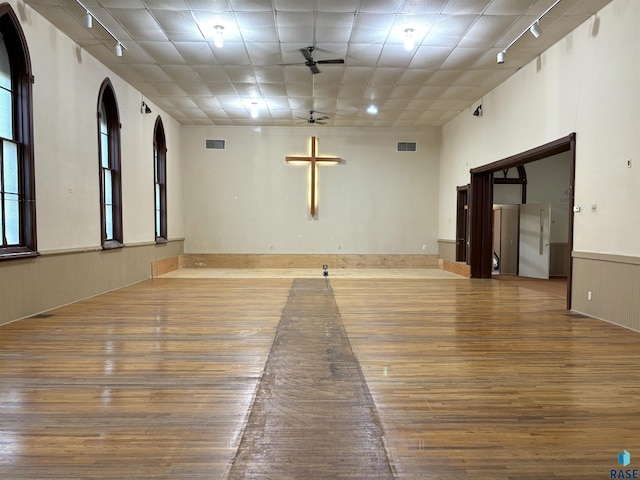 unfurnished room with ceiling fan, rail lighting, and wood walls