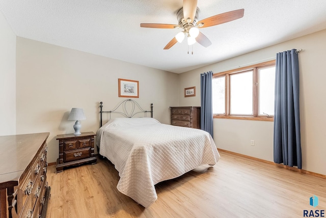 bedroom with ceiling fan, a textured ceiling, and light wood-type flooring