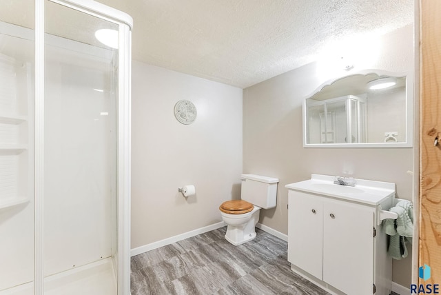 bathroom featuring toilet, a shower with shower door, a textured ceiling, vanity, and hardwood / wood-style floors