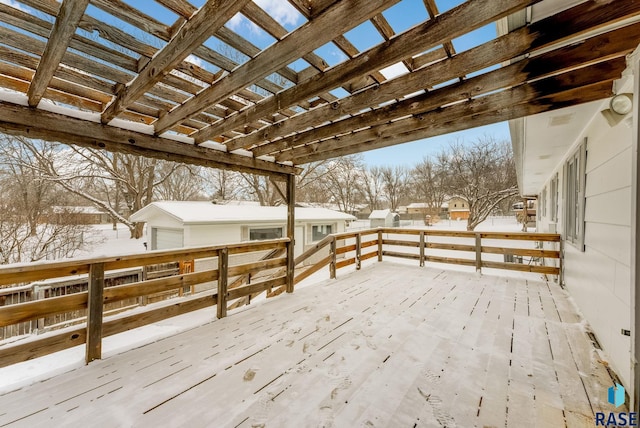 snow covered deck featuring a garage and a pergola