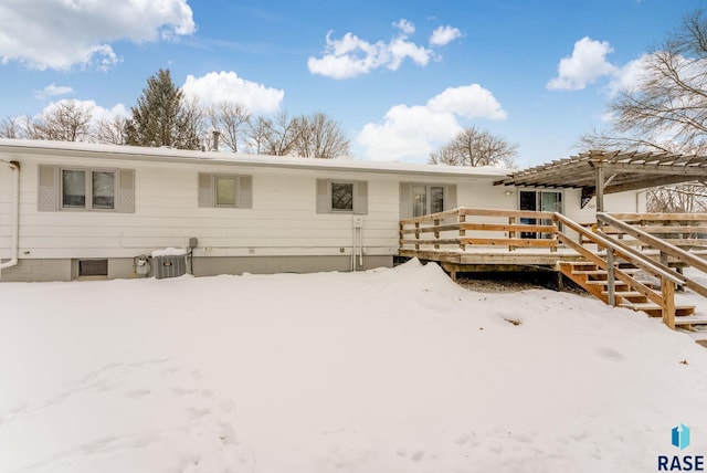 snow covered rear of property featuring a wooden deck and a pergola