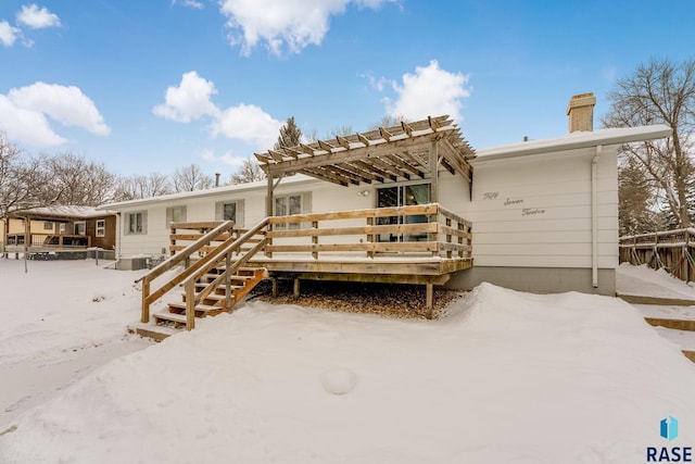 snow covered property with a wooden deck and a pergola