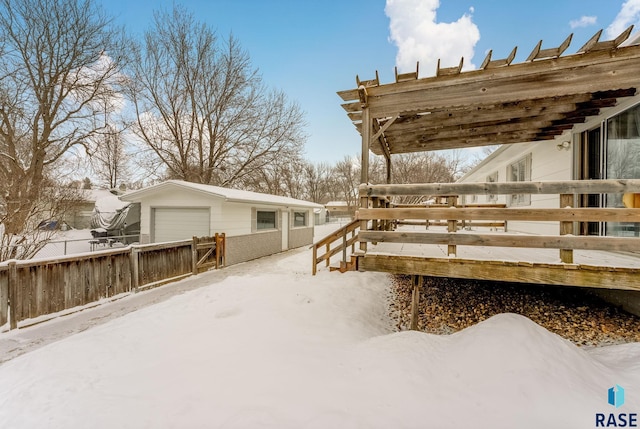 snow covered deck featuring an outbuilding and a garage