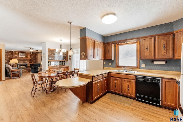 kitchen with sink, hanging light fixtures, black dishwasher, kitchen peninsula, and light wood-type flooring