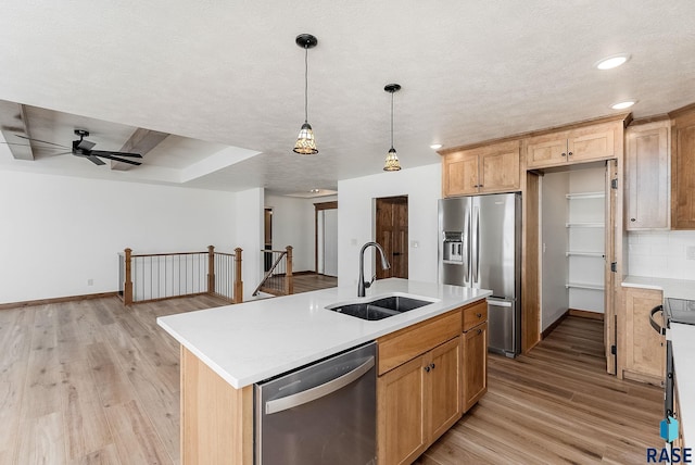 kitchen featuring sink, appliances with stainless steel finishes, light hardwood / wood-style floors, an island with sink, and decorative light fixtures