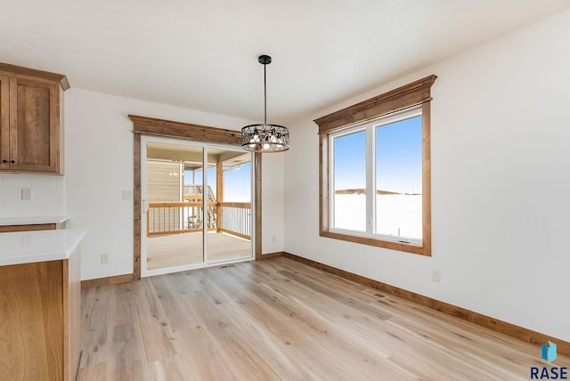 unfurnished dining area with an inviting chandelier and light hardwood / wood-style floors