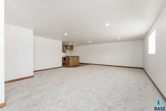 unfurnished living room with light carpet and a textured ceiling