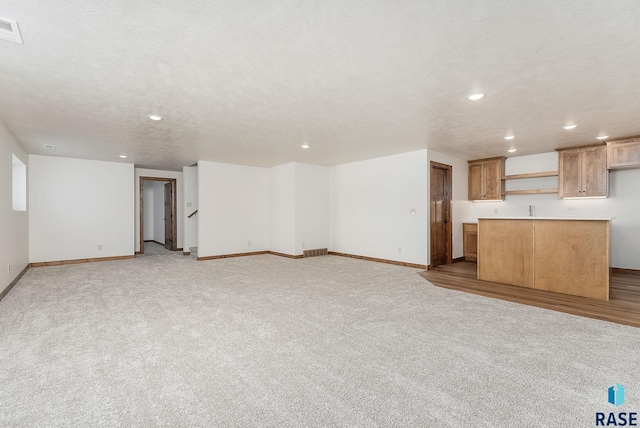 unfurnished living room featuring light carpet and a textured ceiling