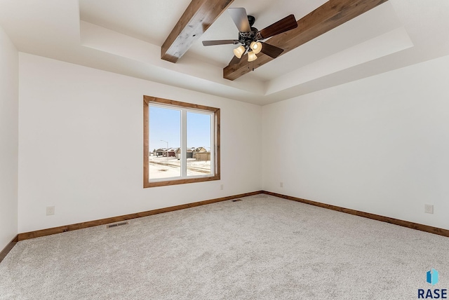 carpeted spare room featuring ceiling fan, beam ceiling, and a tray ceiling