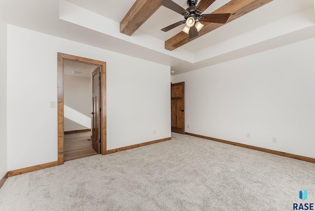 spare room featuring beamed ceiling, light carpet, and ceiling fan