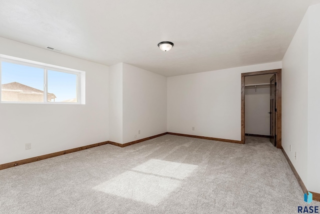 unfurnished bedroom with a walk in closet, a closet, and carpet flooring