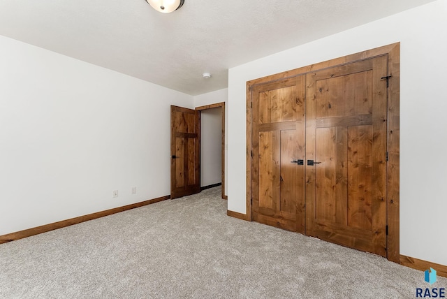 unfurnished bedroom featuring light colored carpet, a closet, and a textured ceiling