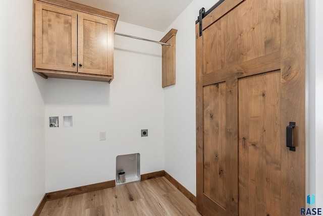 clothes washing area featuring hookup for a washing machine, cabinets, light hardwood / wood-style floors, a barn door, and hookup for an electric dryer