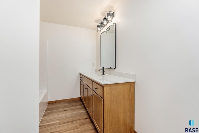 bathroom with hardwood / wood-style flooring, vanity, and a tub