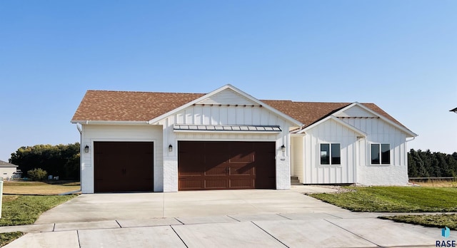 modern inspired farmhouse featuring a garage and a front yard