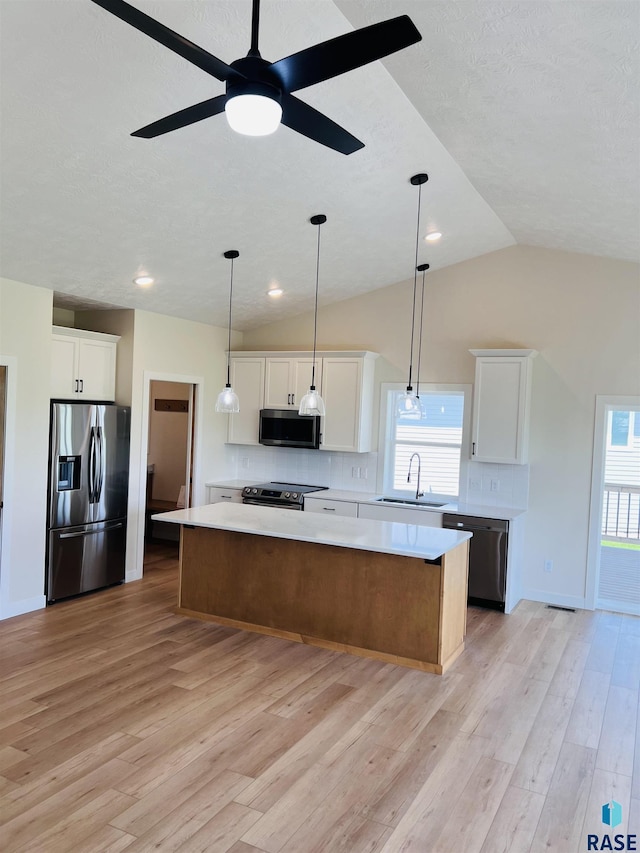 kitchen with a kitchen island, white cabinets, and appliances with stainless steel finishes