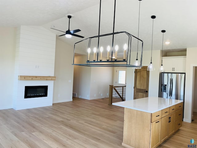 kitchen featuring pendant lighting, a fireplace, white cabinets, a center island, and stainless steel fridge with ice dispenser