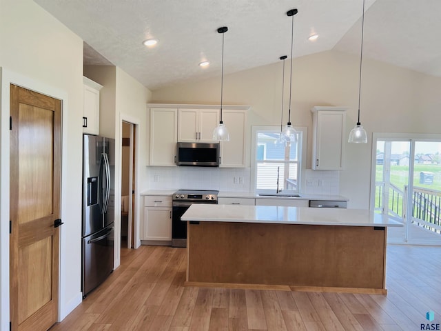 kitchen featuring white cabinetry, decorative light fixtures, stainless steel appliances, and a kitchen island