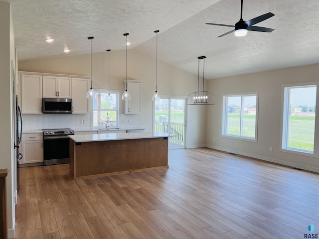 kitchen featuring pendant lighting, appliances with stainless steel finishes, a kitchen island, and white cabinets