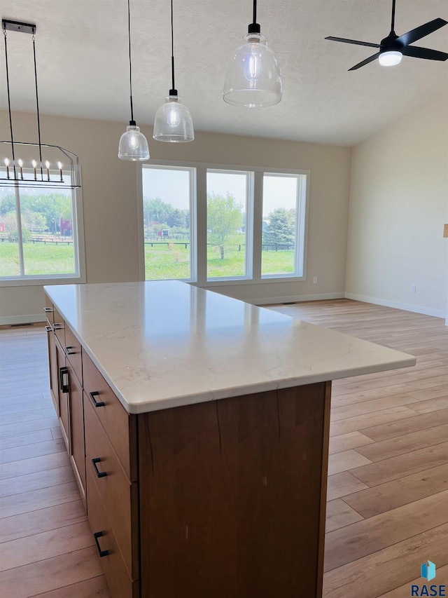 kitchen featuring light stone countertops, light hardwood / wood-style flooring, and decorative light fixtures