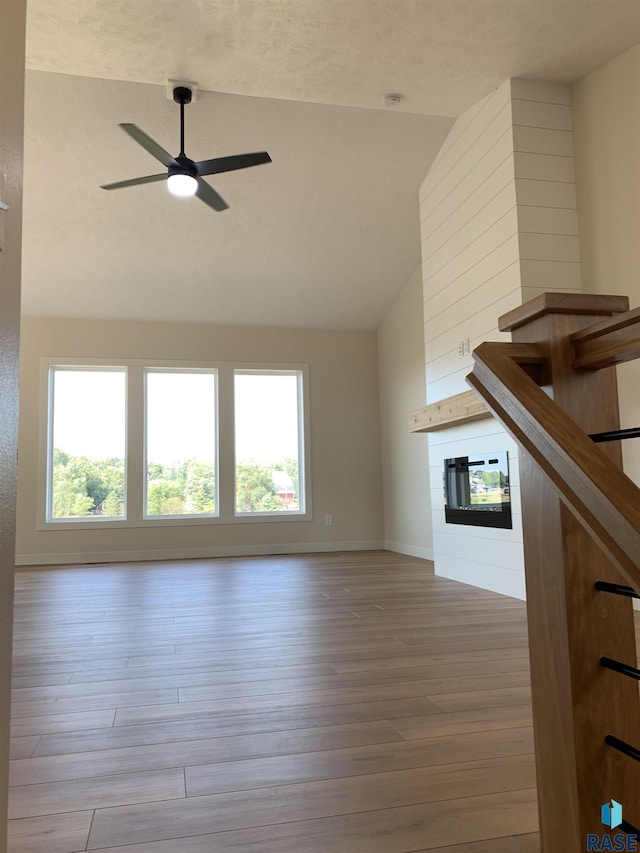 unfurnished living room with ceiling fan, high vaulted ceiling, a wealth of natural light, and light wood-type flooring