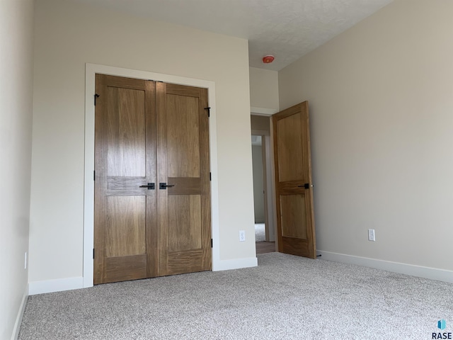 unfurnished bedroom featuring light colored carpet and a closet