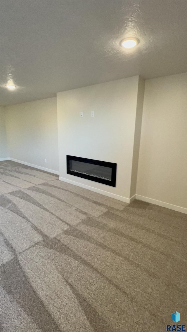 unfurnished living room with carpet floors and a textured ceiling