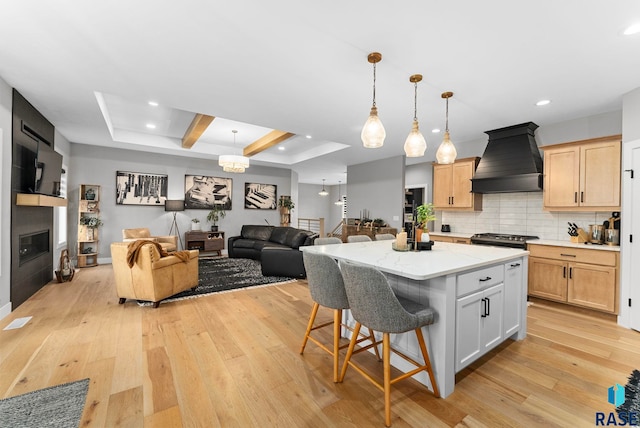 kitchen featuring premium range hood, a center island, hanging light fixtures, and light brown cabinets