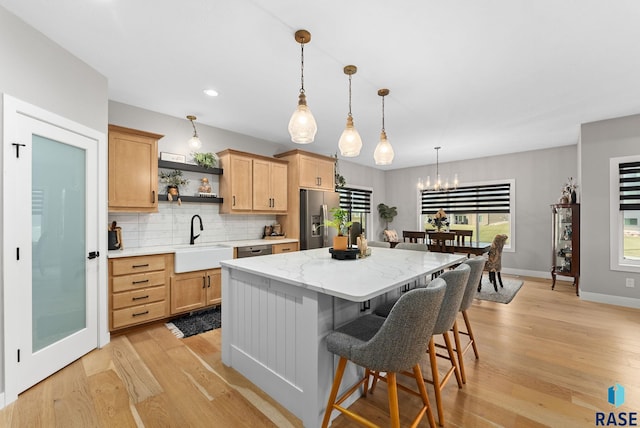 kitchen with sink, appliances with stainless steel finishes, a kitchen island, pendant lighting, and backsplash