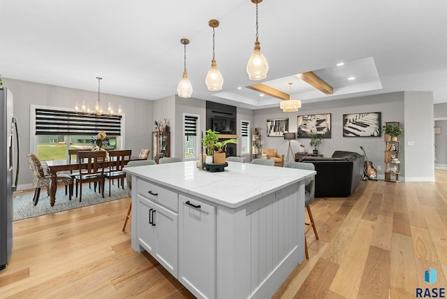 kitchen with pendant lighting, a kitchen bar, a kitchen island, and white cabinets