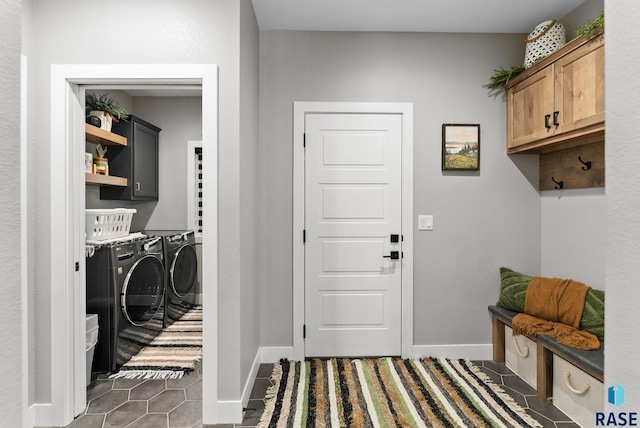 laundry room featuring cabinets, dark tile patterned flooring, and washing machine and dryer