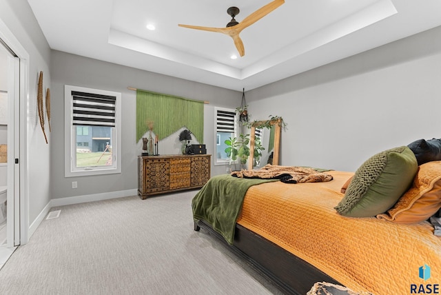 carpeted bedroom featuring a tray ceiling and ceiling fan